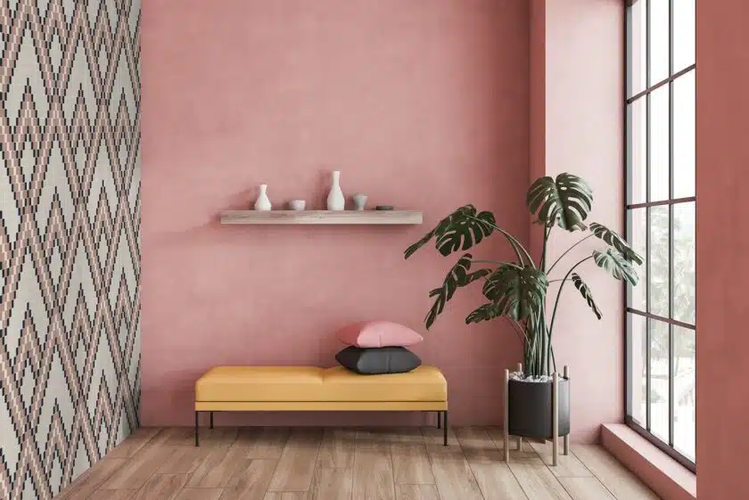 Minimalistic pink living room interior with wooden floor, tall window and yellow bench with cushions and shelf with vases above it. 3d rendering